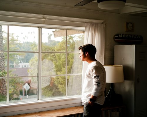 A person opening a window in the morning to let natural light in